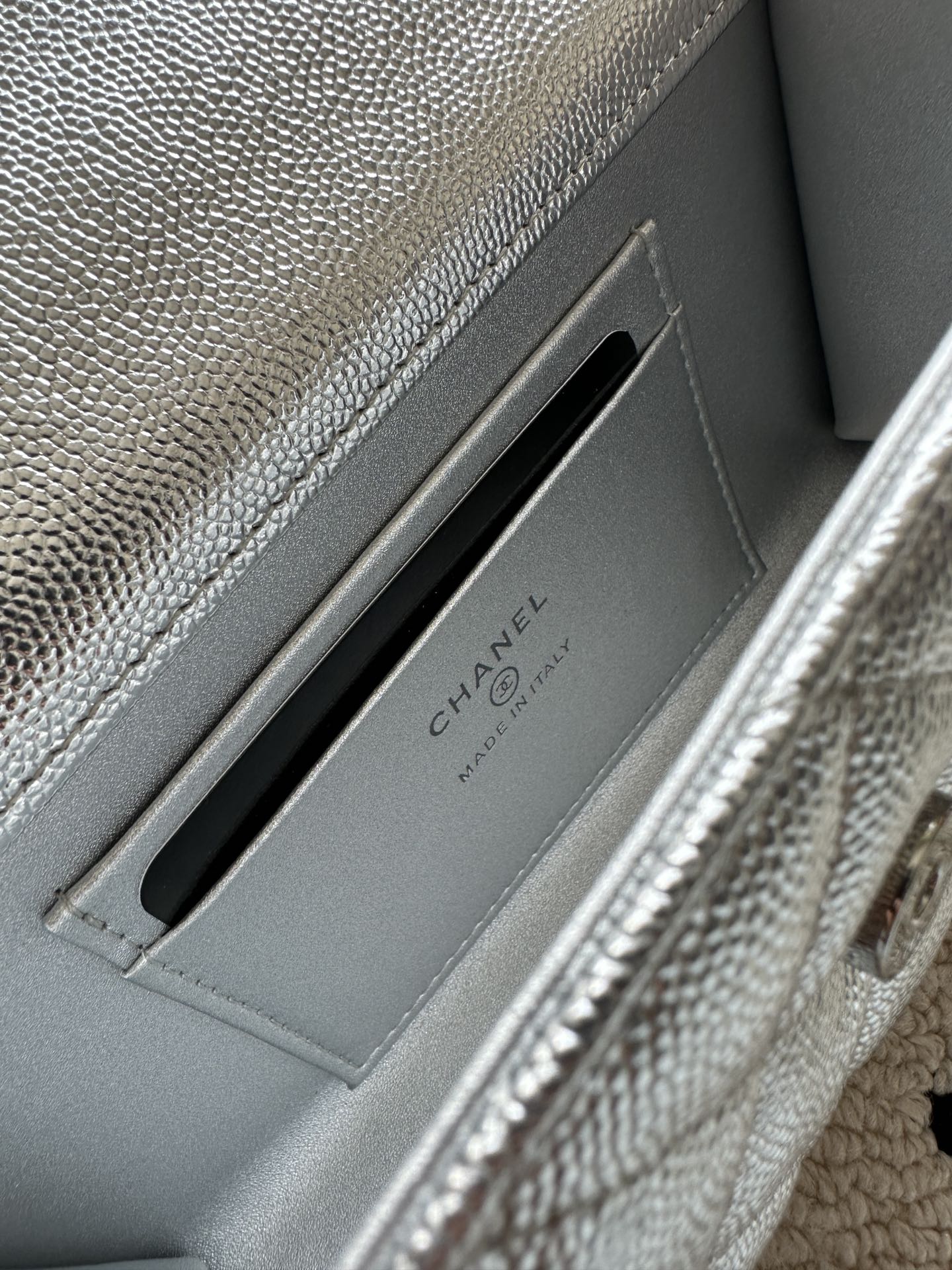 Light silver bag interior card slot with Chanel text branding on divider