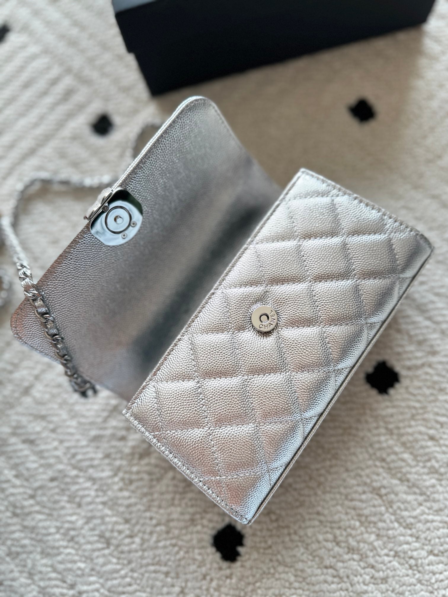 Light silver quilted wallet-style bag with chain strap and snap front closure