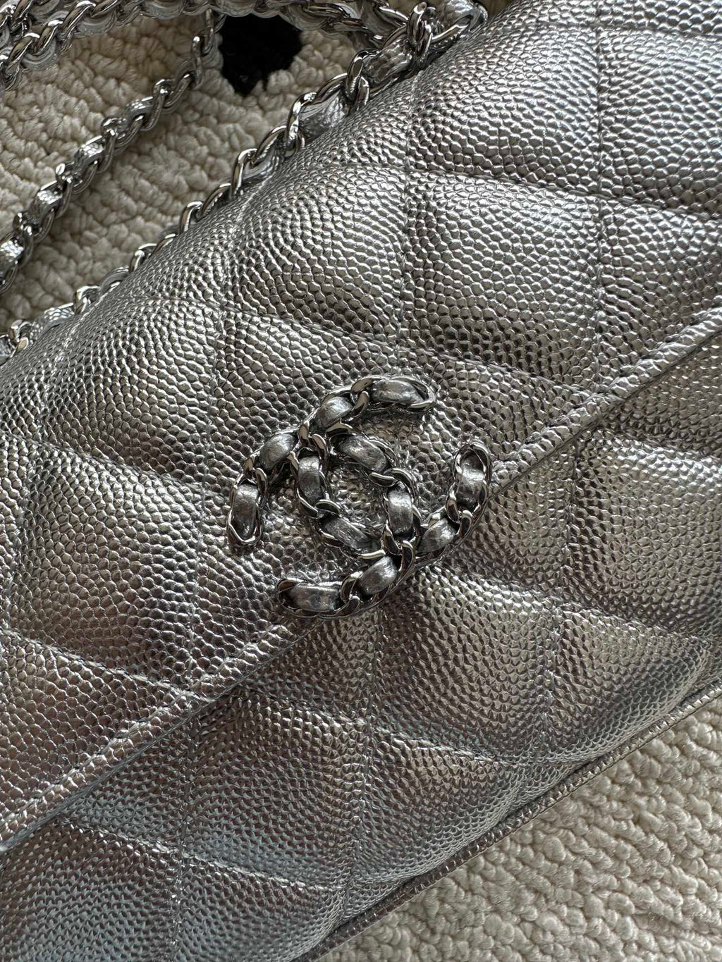 Light silver quilted bag close-up with braided chain and central clasp detail