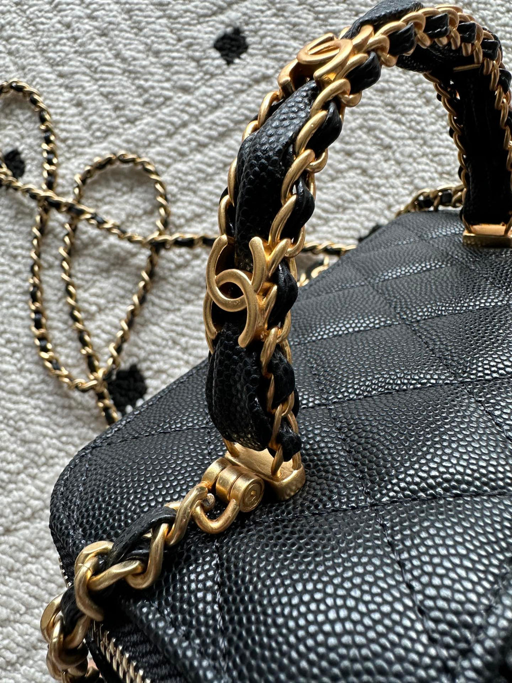 Black quilted bag with gold chain top handle and zipper trim