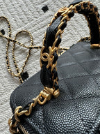 Black quilted bag with gold chain top handle and zipper trim