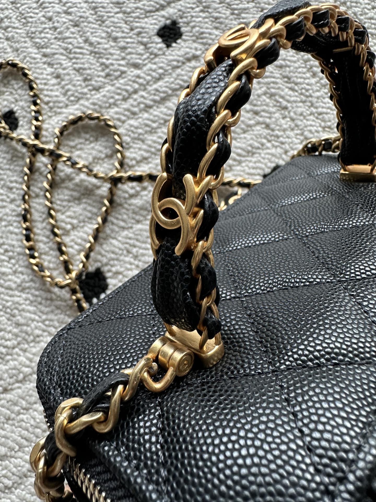 Black quilted bag with gold chain top handle and zipper trim