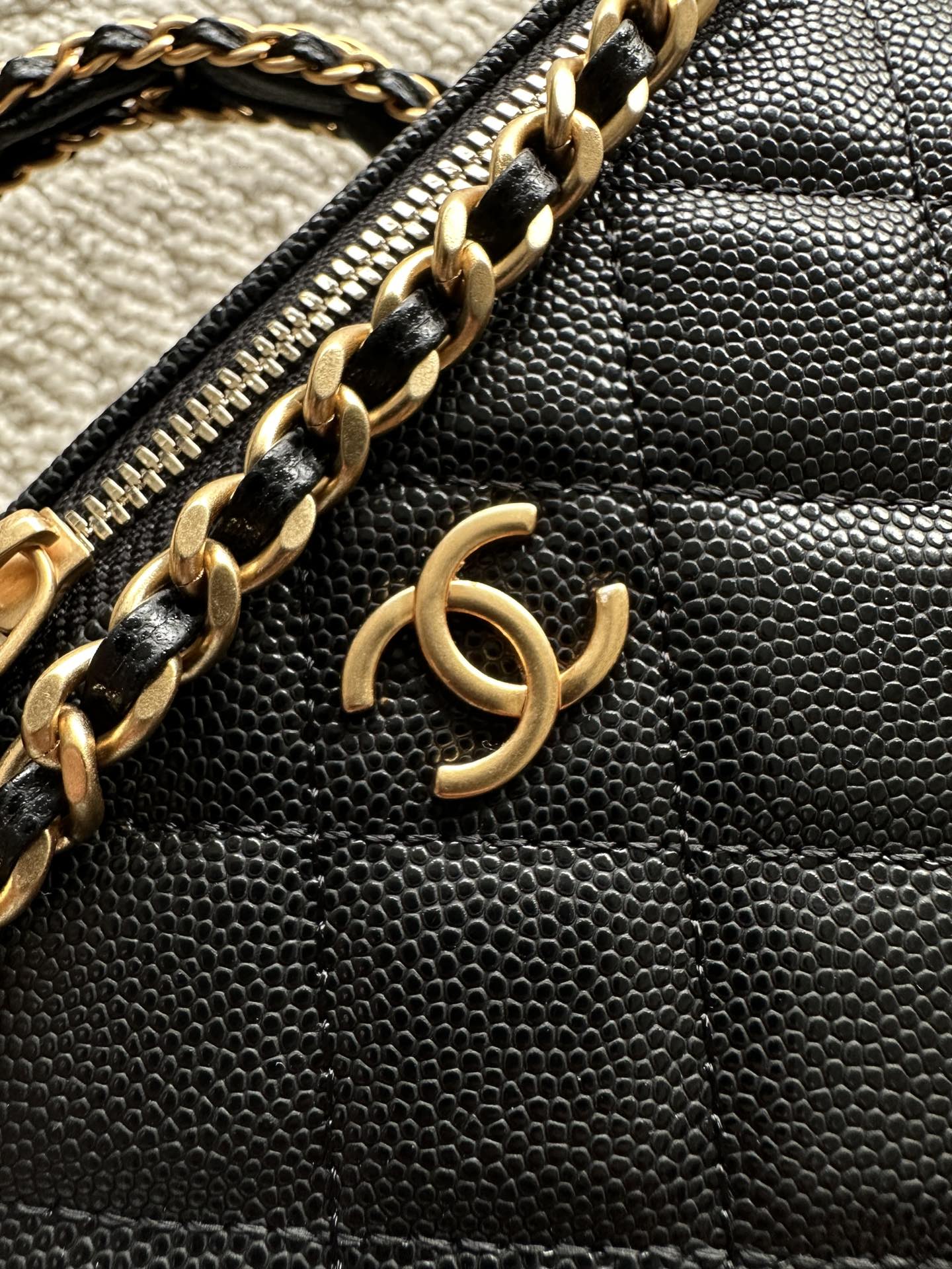 Black leather zipper pouch with gold chain detail and CC charm on front