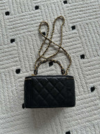 Small black quilted handbag with gold chain strap and CC logo on front