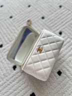 White quilted zip mini handbag open, showing blue-lined interior pocket