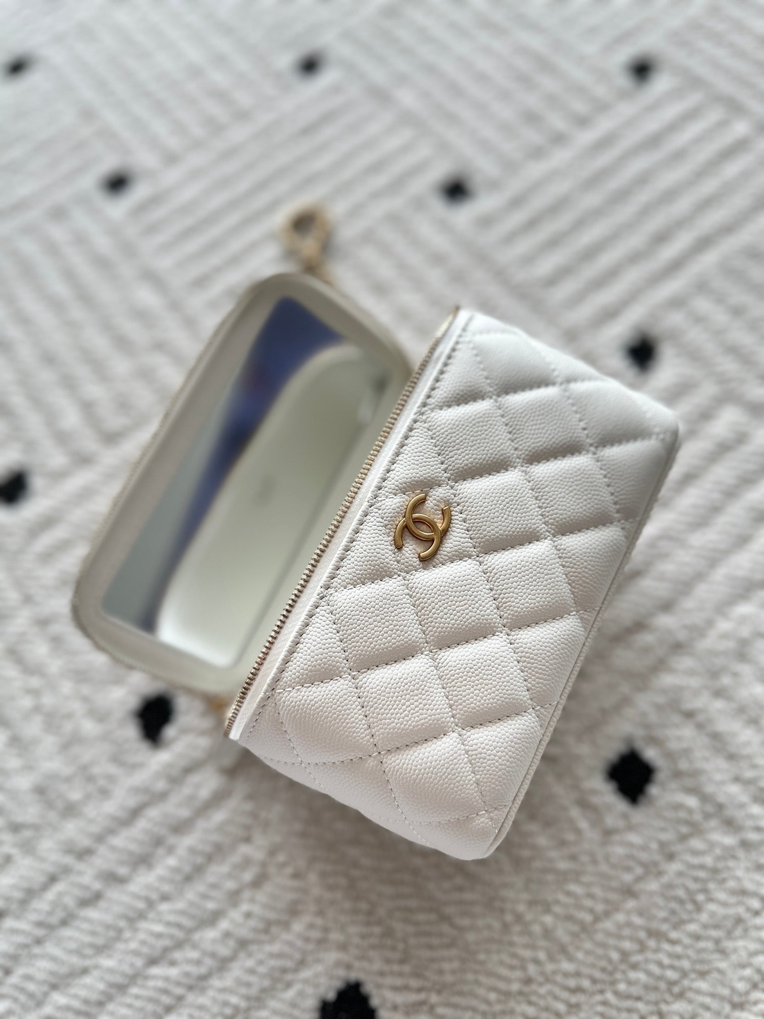 White quilted zip mini handbag open, showing blue-lined interior pocket