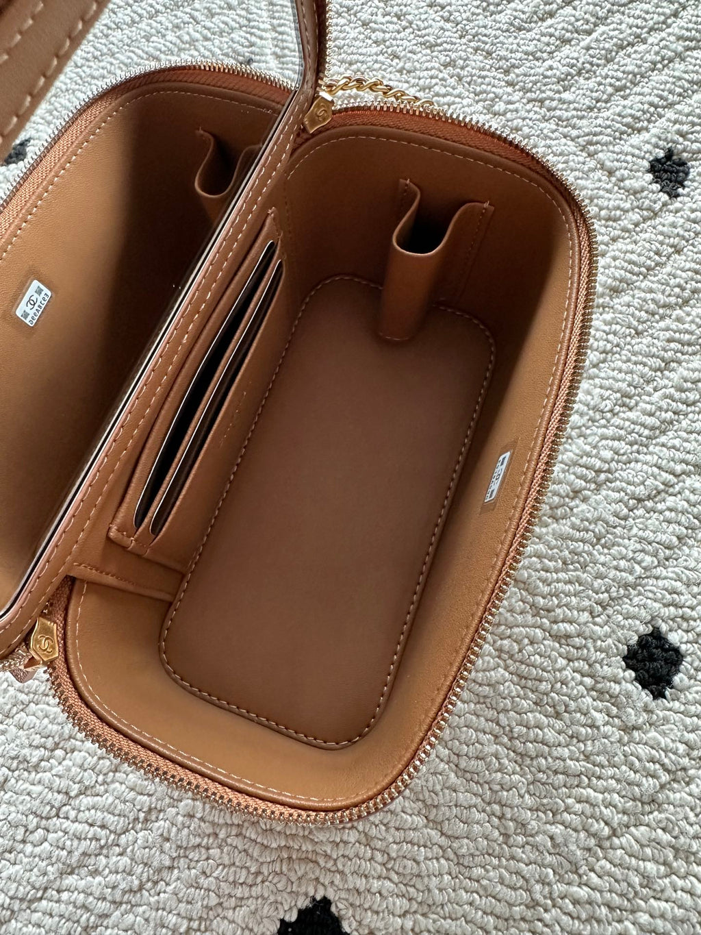 Chanel bag interior view in tan-brown leather with card slots and zip pocket.