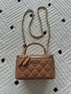 Chanel bag in tan-brown quilted leather with chain strap and top clasp.
