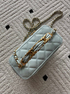 Light-blue mini quilted crossbody bag with gold chain strap and flap-style front