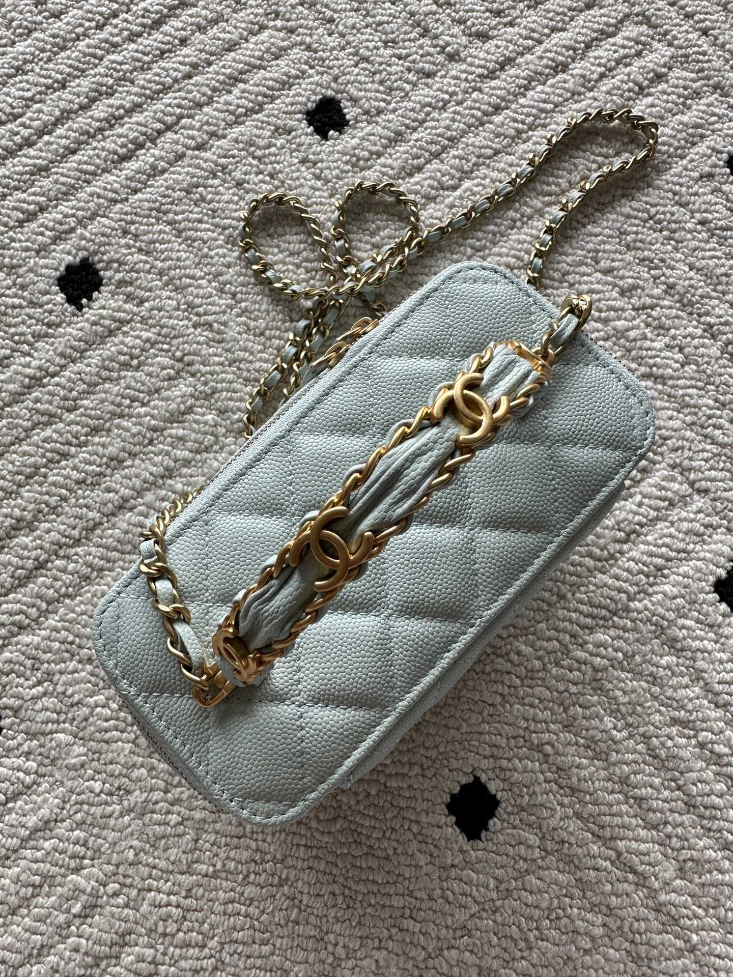 Light-blue mini quilted crossbody bag with gold chain strap and flap-style front