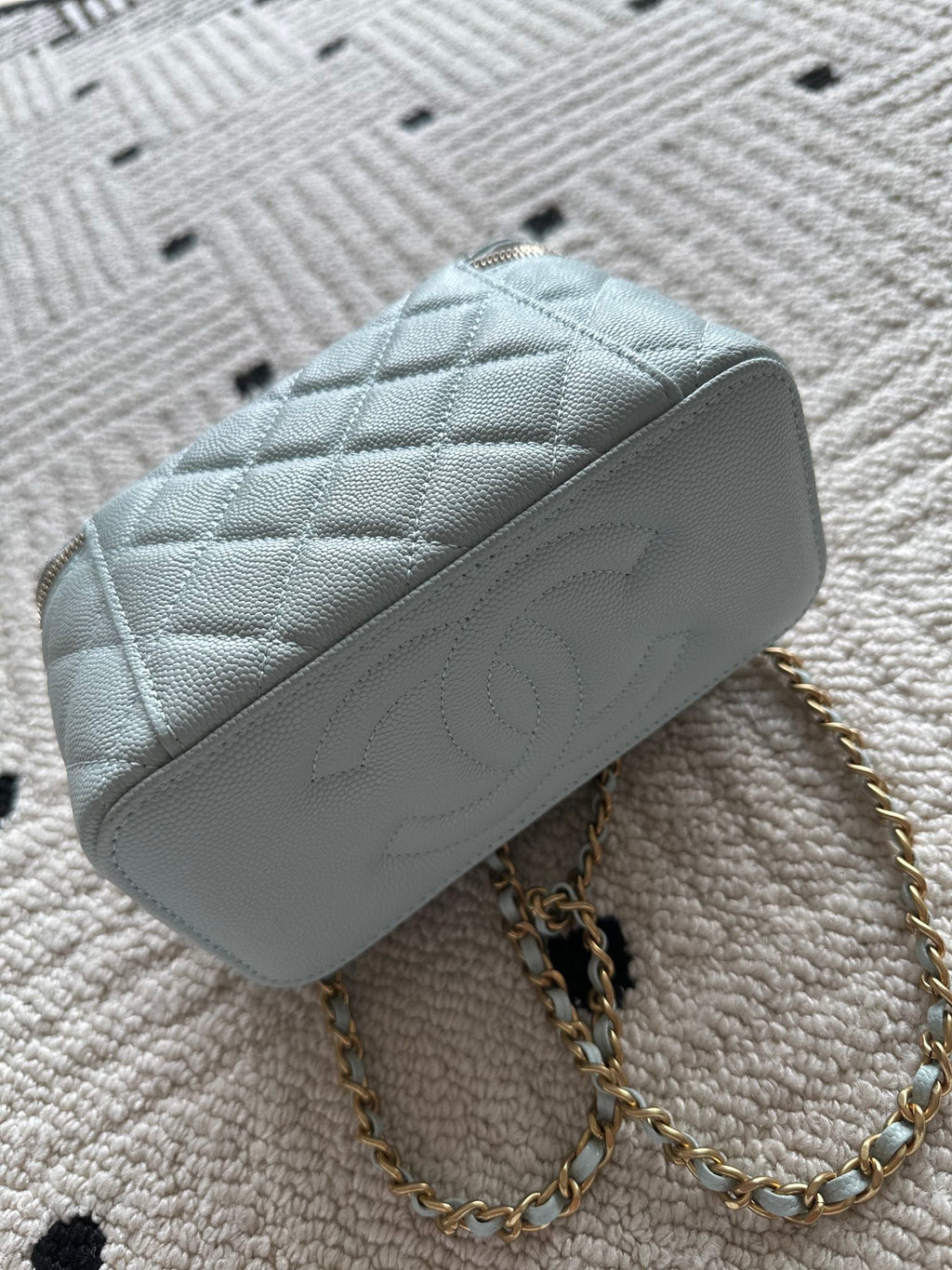 Light-blue quilted mini shoulder bag with gold chain strap and top zip opening