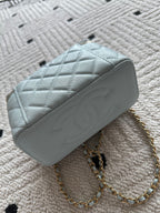 Light-blue quilted mini shoulder bag with gold chain strap and top zip opening