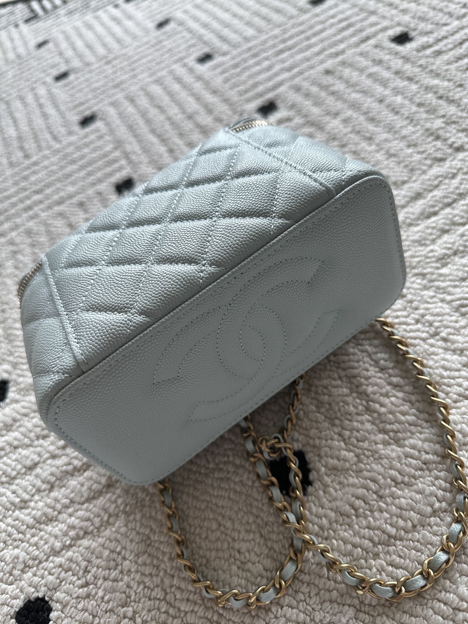 Light-blue quilted mini shoulder bag with gold chain strap and top zip opening