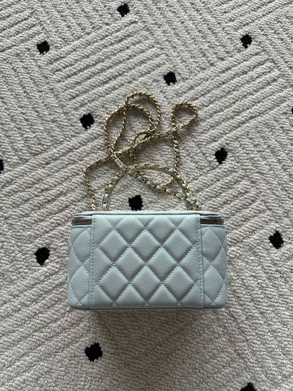 Quilted light-blue mini bag with gold chain shoulder strap and top zip closure