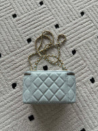 Quilted light-blue mini bag with gold chain shoulder strap and top zip closure