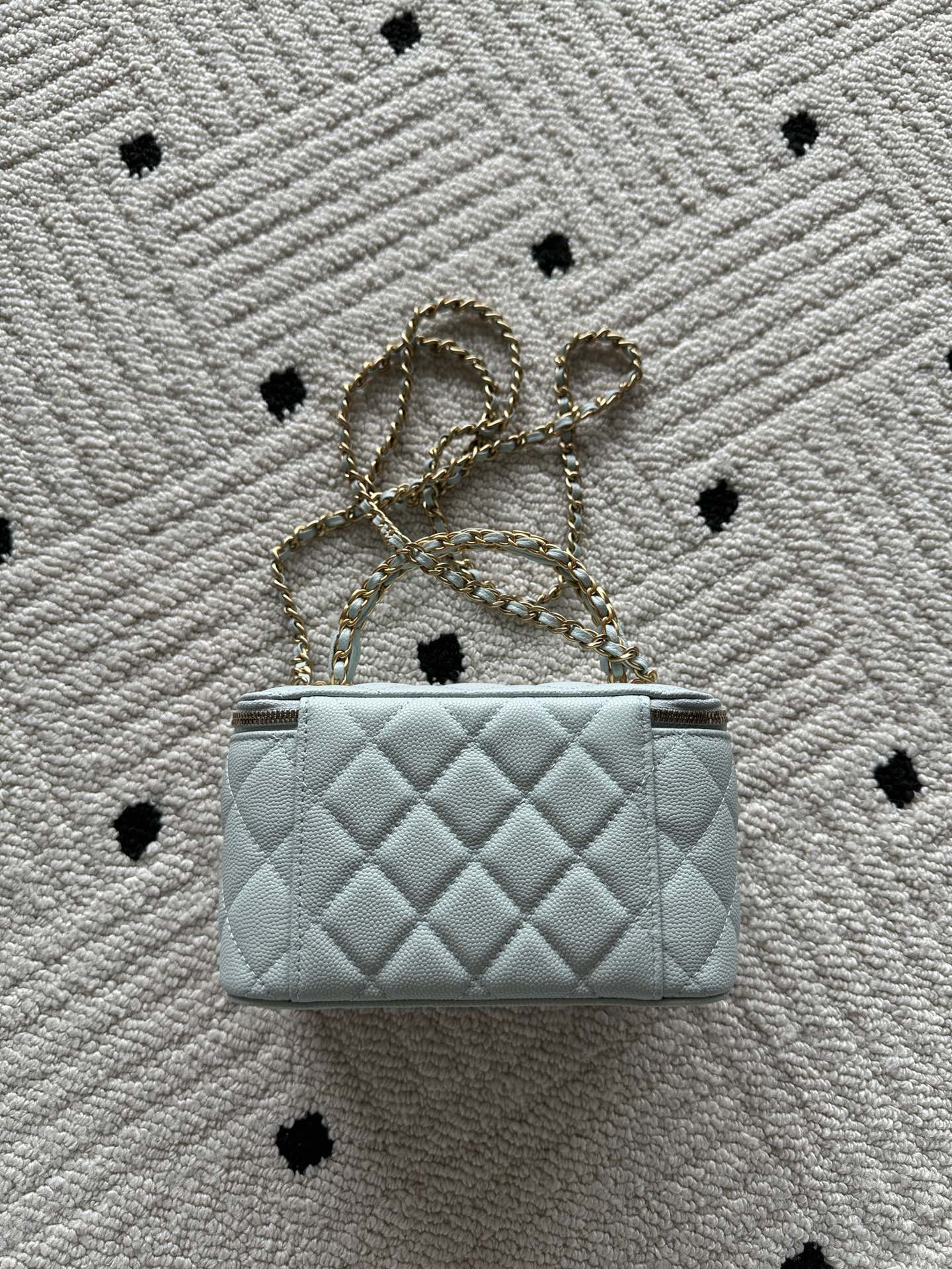 Quilted light-blue mini bag with gold chain shoulder strap and top zip closure