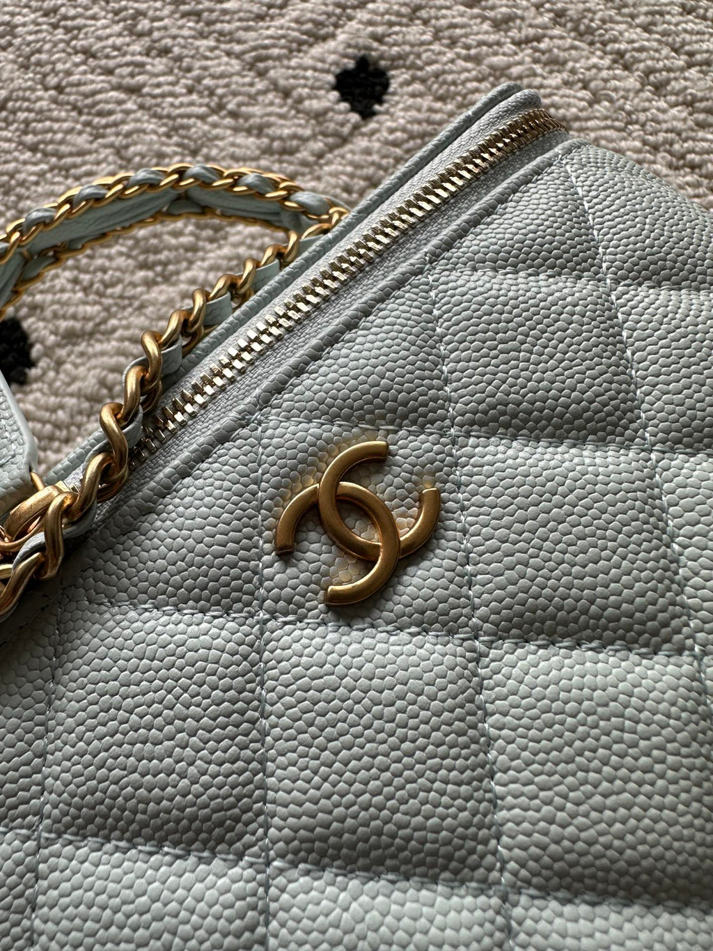 Light-blue quilted mini bag with gold-tone logo on flap and top zipper detail