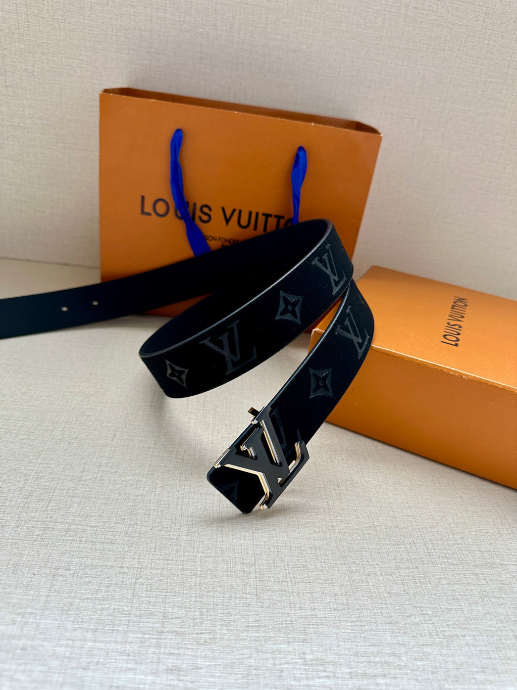 Louis Vuitton navy monogram belt with large gold-tone buckle, angled view