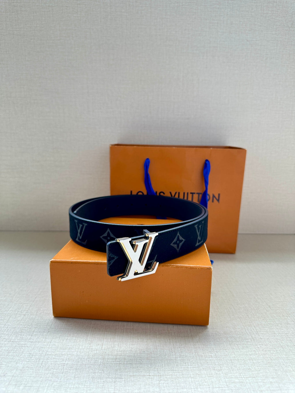 Louis Vuitton navy monogram belt with gold-tone LV buckle on top of box