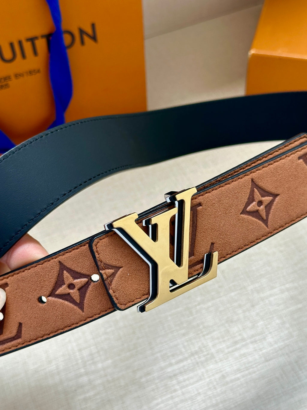 Louis Vuitton belt close-up: brown monogram strap with gold-tone LV buckle