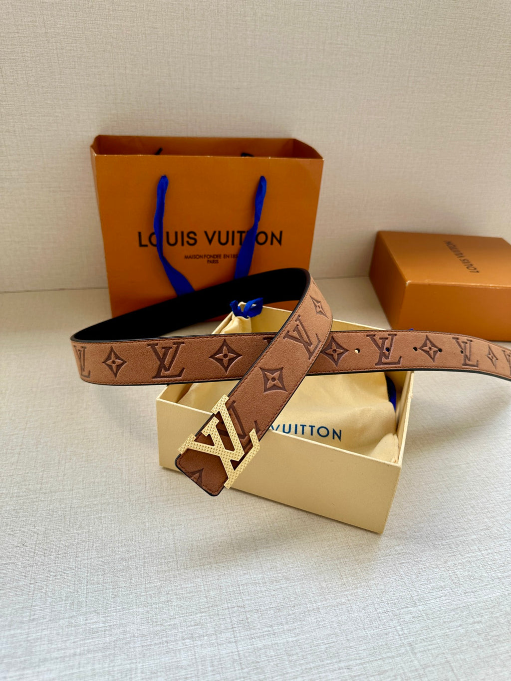 Louis Vuitton monogram belt with tan strap and gold-tone buckle, belt ends shown