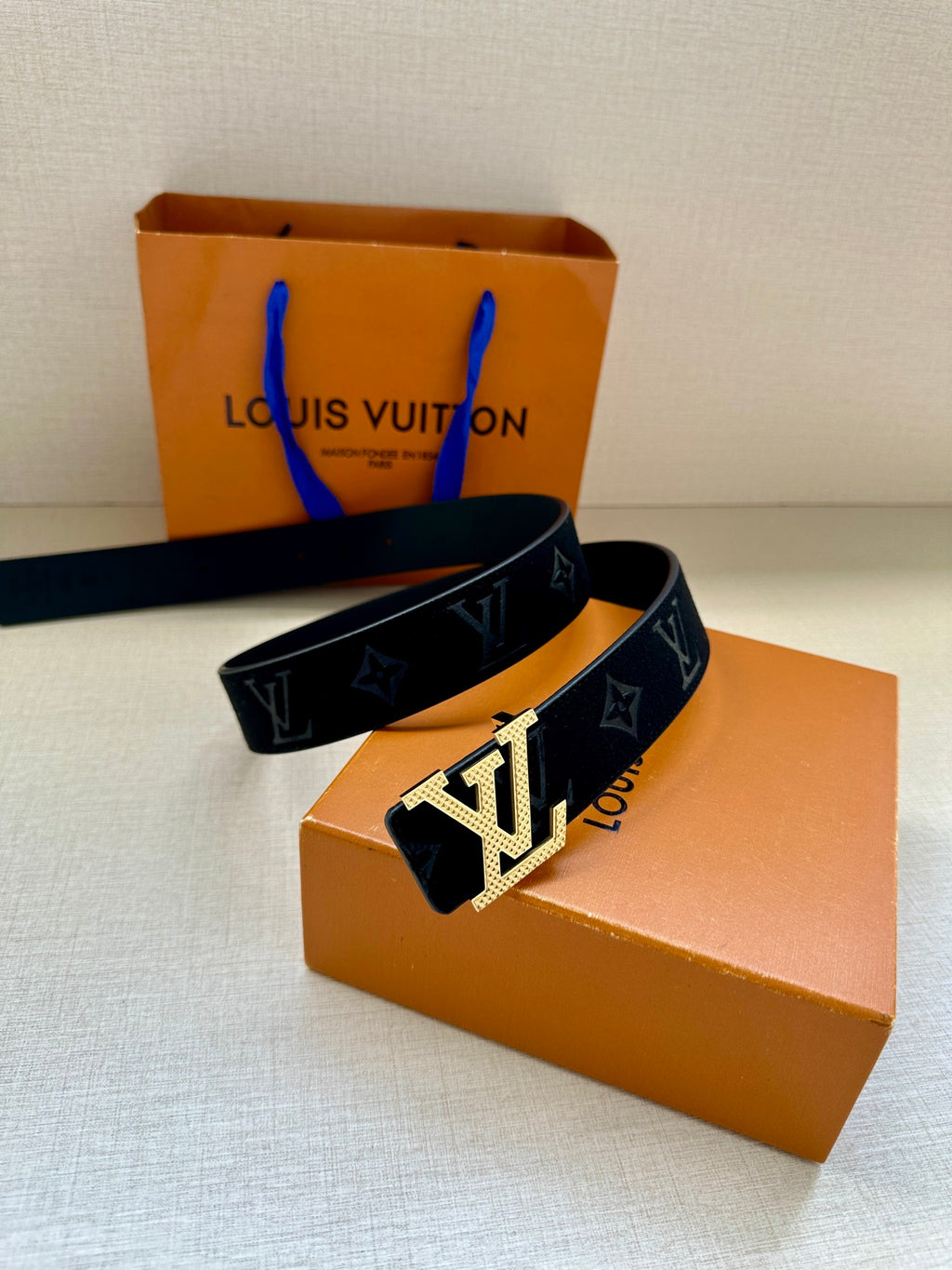 Dark blue patterned belt with silver LV buckle; belt end and strap details visible.