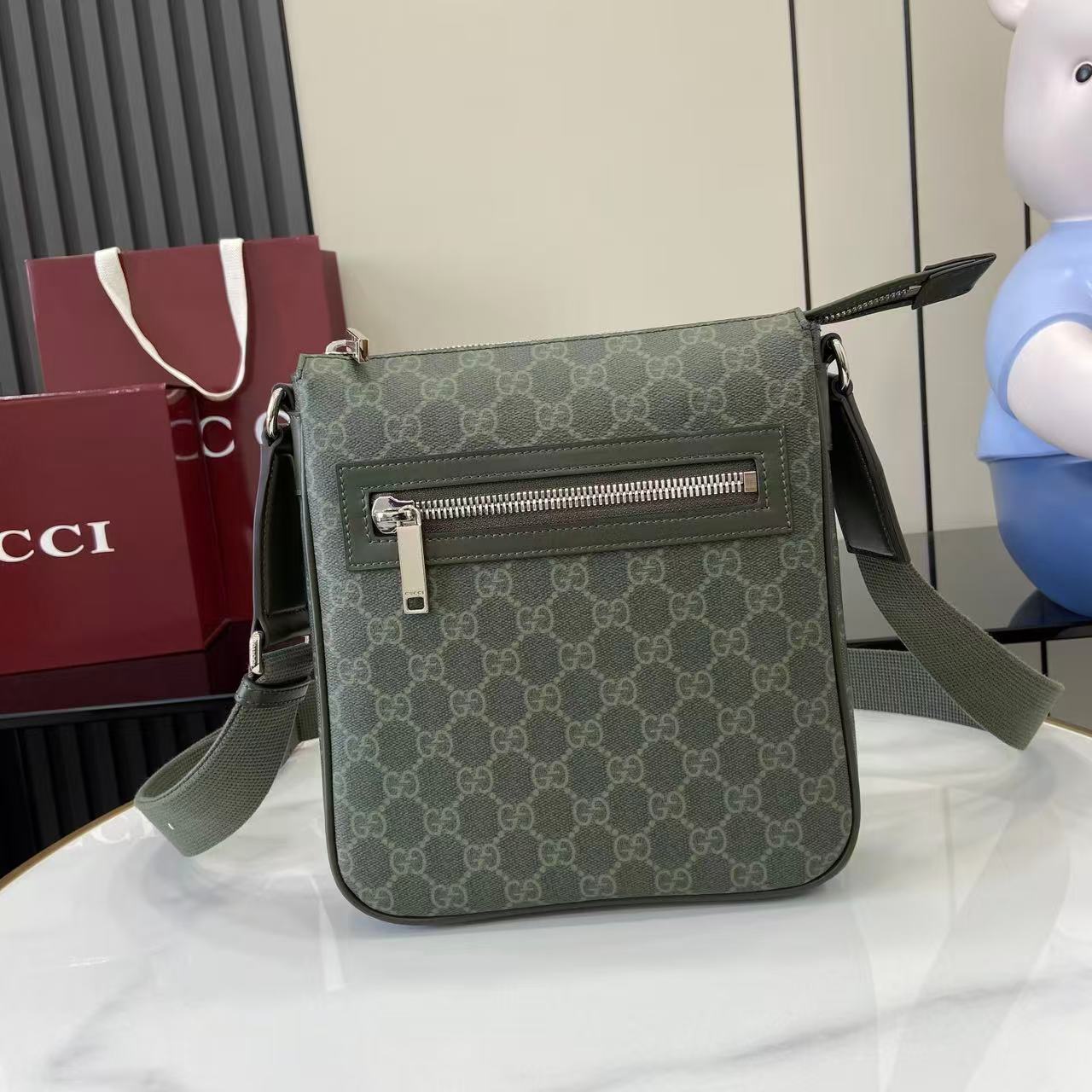 Crossbody bag with green GG-style monogram, front flap and silver zipper, adjustable strap