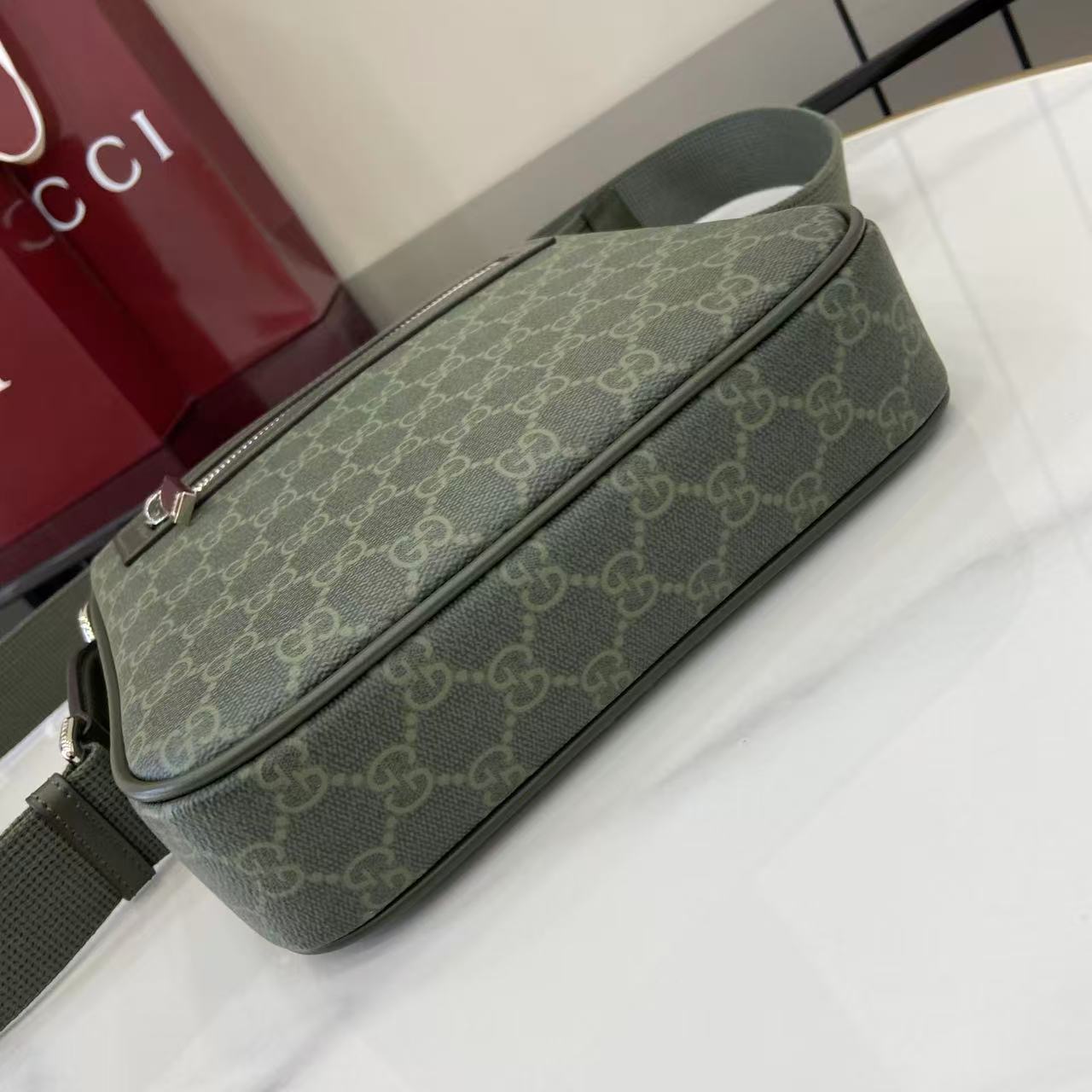 Crossbody bag with green GG-style monogram and long top zip detail
