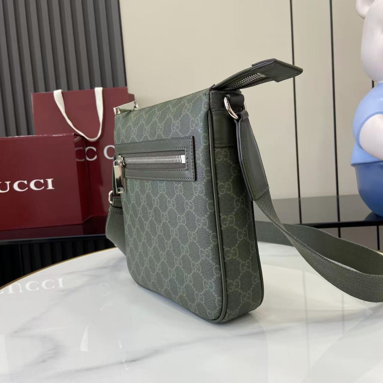 Crossbody bag three-quarter view with green GG-style monogram and wide shoulder strap