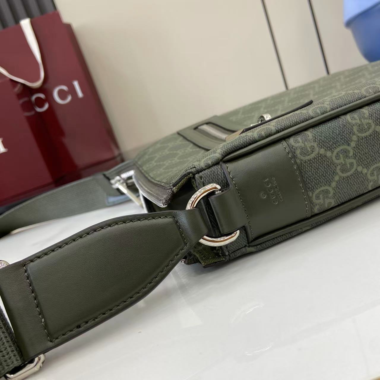 Crossbody bag strap attachment detail with green leather and silver hardware