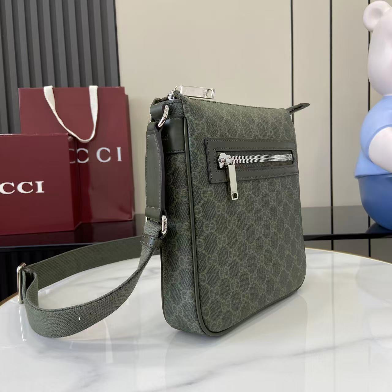 Crossbody bag side view with green GG-style monogram and front silver zipper pocket