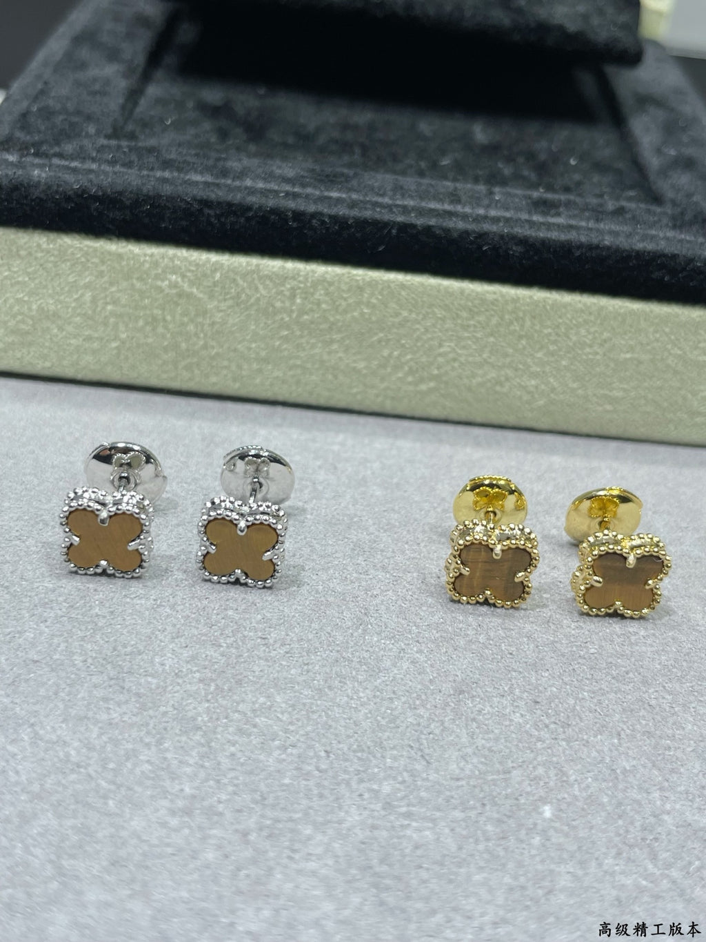 Clover stud earrings showing silver and gold tones on tray