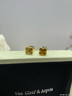 Gold-tone clover stud earrings on black velvet display