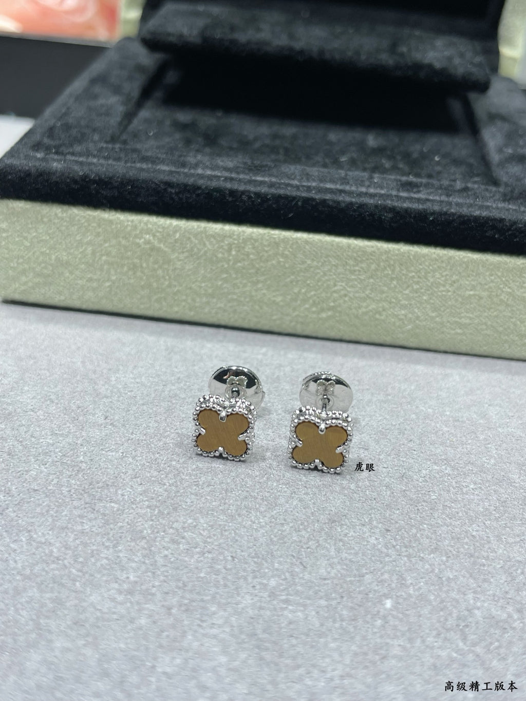 Silver-tone clover stud earrings on display tray