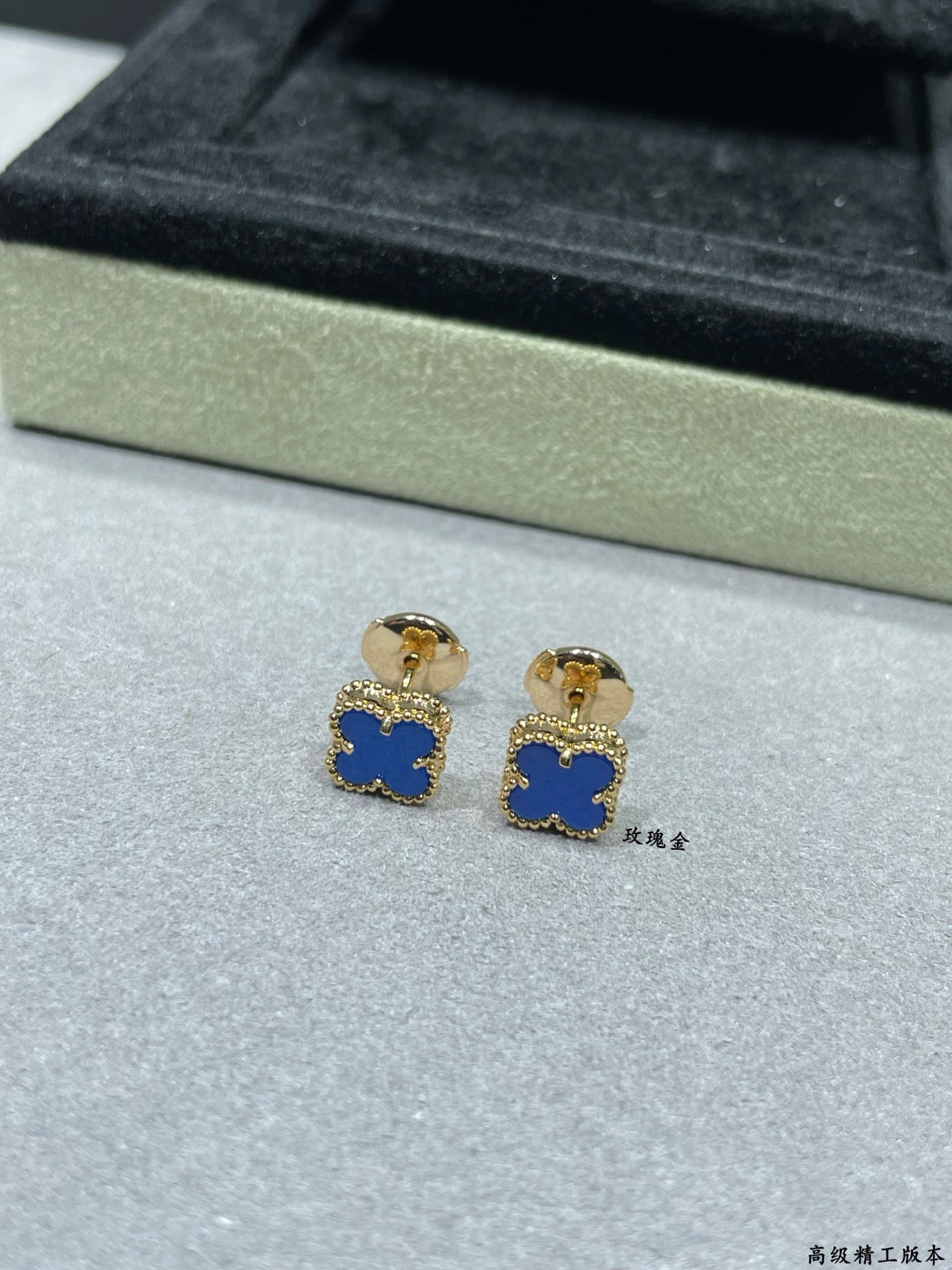 Clover enamel stud earrings with blue centers and gold-tone posts in box