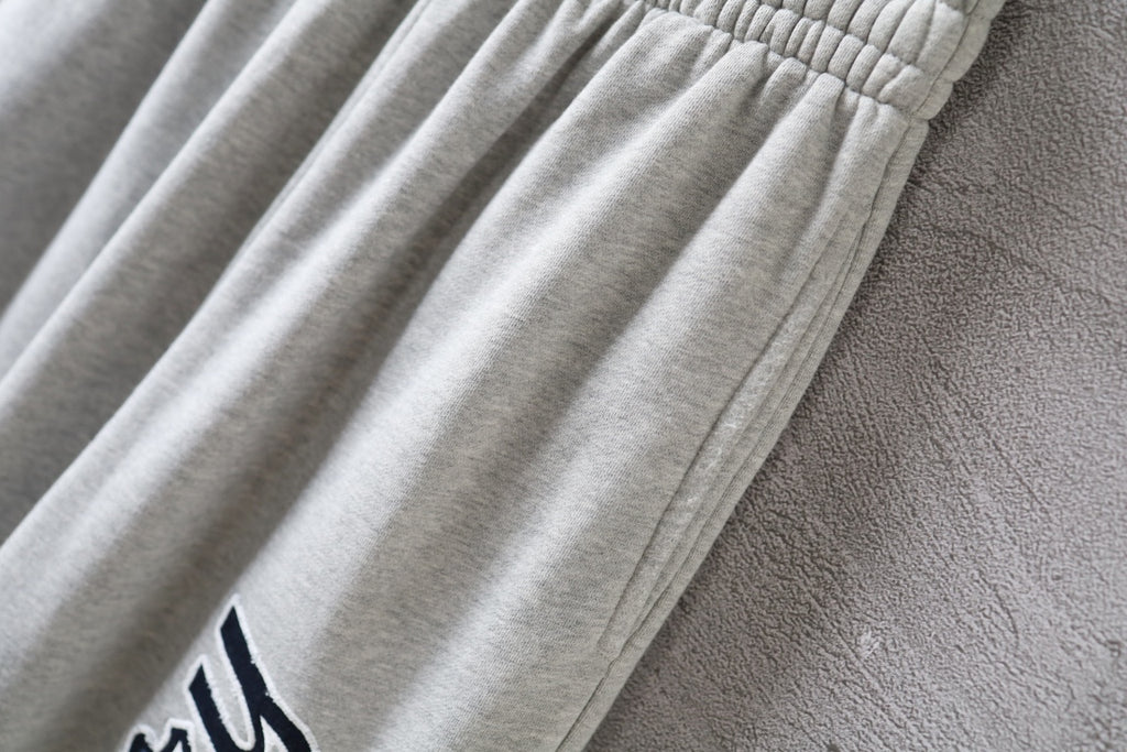 Balenciaga pants detail with gathered fabric folds on light gray leg
