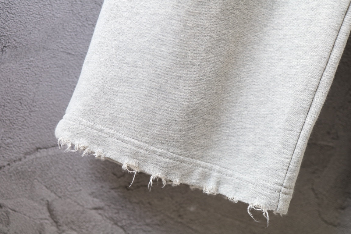 Balenciaga pants hem with frayed edge on light gray fabric