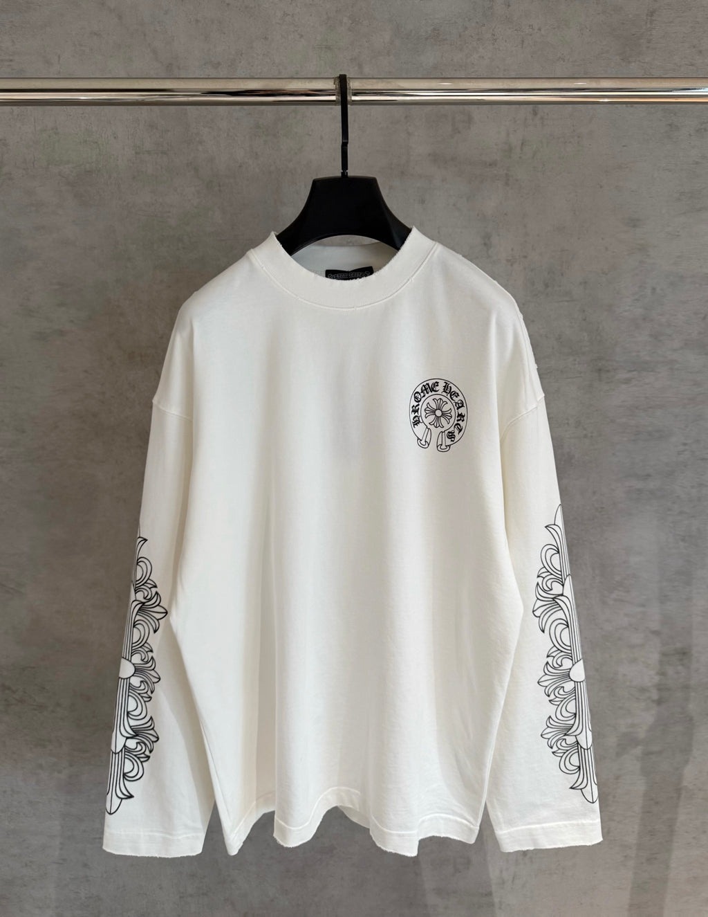White long-sleeve graphic T-shirt with small chest emblem and sleeve scroll prints