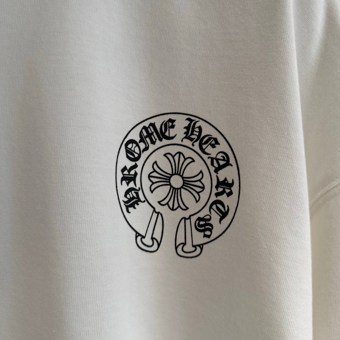 White long-sleeve T-shirt close-up of small circular chest logo