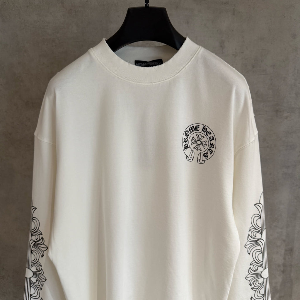 White long-sleeve graphic T-shirt with small chest emblem and ornate sleeve artwork