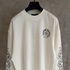 White long-sleeve graphic T-shirt with small chest emblem and ornate sleeve artwork