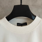 White long-sleeve T-shirt neckline close-up with black brand label inside collar