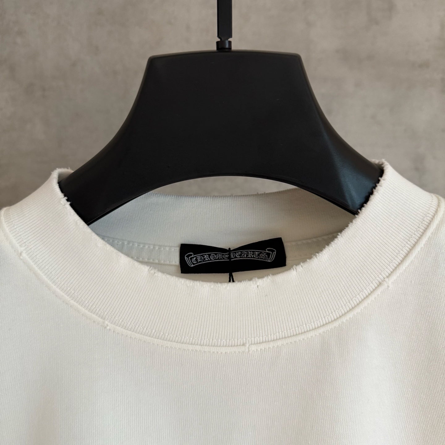 White long-sleeve T-shirt neckline close-up with black brand label inside collar