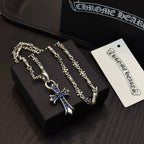 Silver cross pendant necklace with blue enamel charm displayed in a box