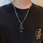 Silver cross pendant necklace with blue enamel charm worn on a black shirt