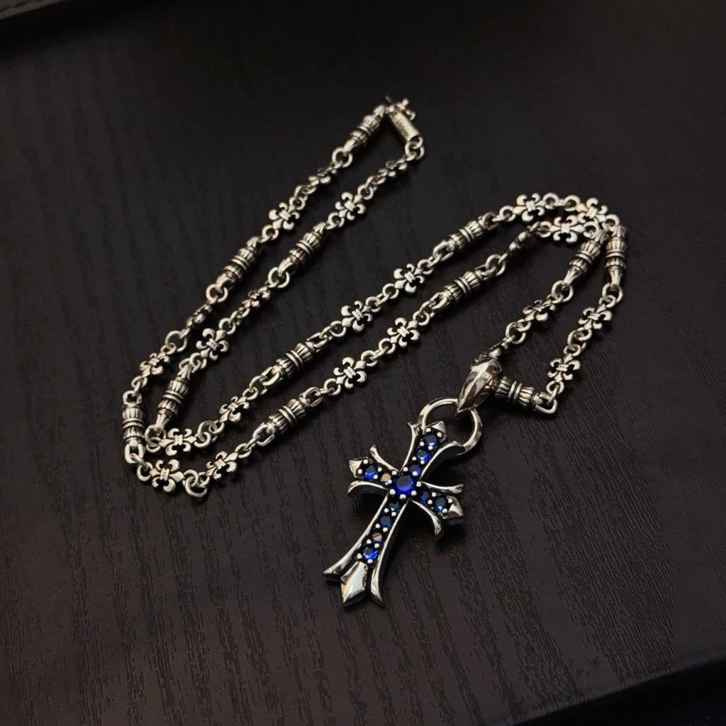 Two silver cross pendant necklaces with blue enamel charms on linked chains
