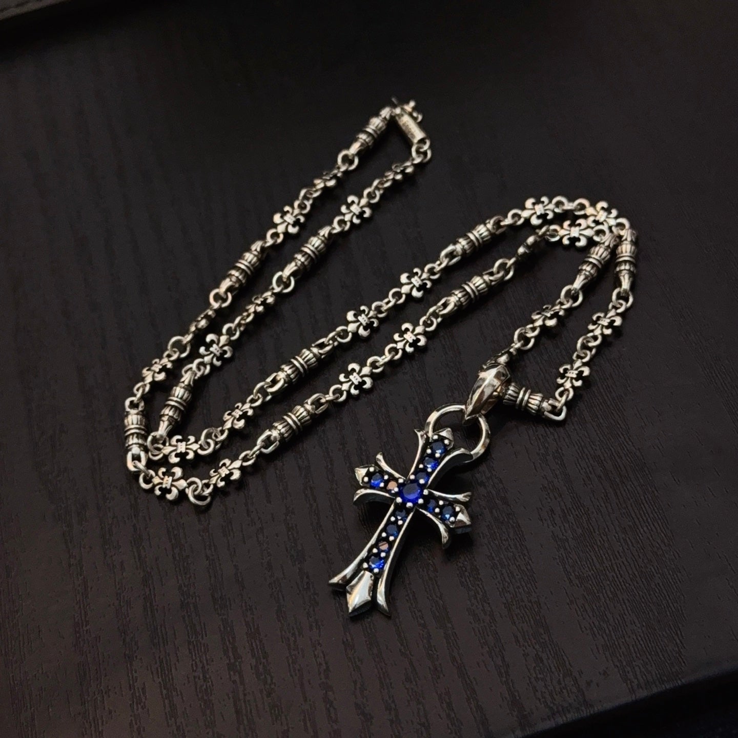Two silver cross pendant necklaces with blue enamel charms on linked chains