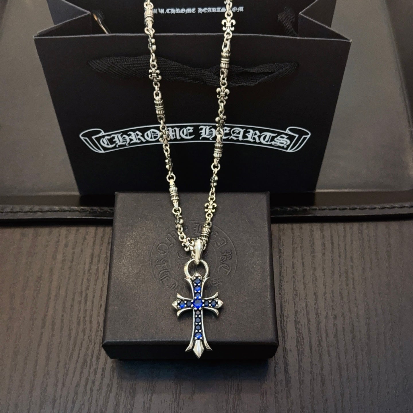 Silver cross pendant necklace with blue stone accents on a chain