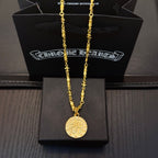 Gold-tone long necklace with round coin pendant on black jewelry box