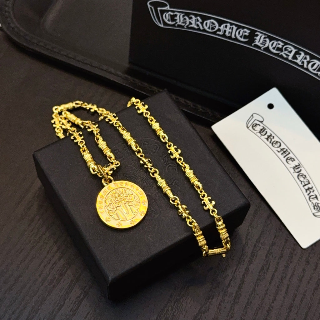 Gold-tone coin pendant necklace with matching chain bracelets on black tray